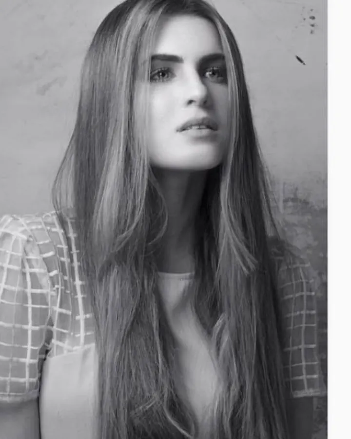 Femme aux cheveux blonds, en photo noir et blanc, regardant vers le haut, portant une chemise à carreaux
