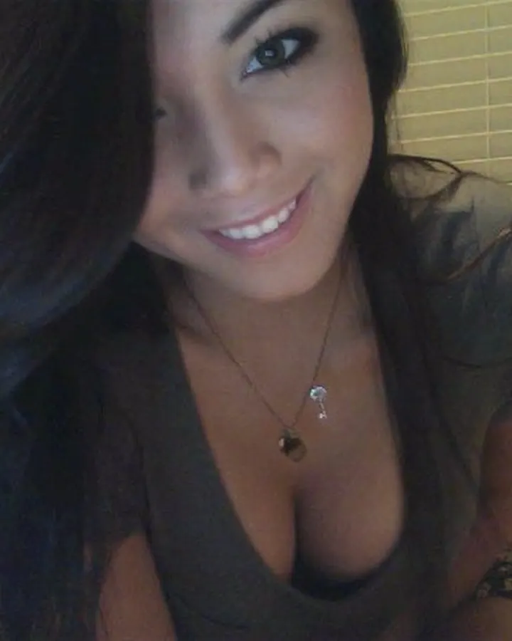 Jeune femme asiatique souriante, cheveux foncés, portant un haut transparent, allongée sur un lit