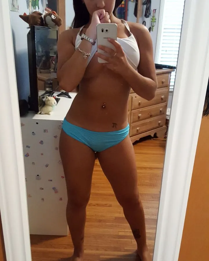 Jeune femme indienne en haut blanc, prenant un selfie devant un miroir dans une chambre