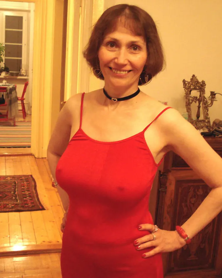 Femme en robe rouge, souriante, posant dans un couloir décoré.